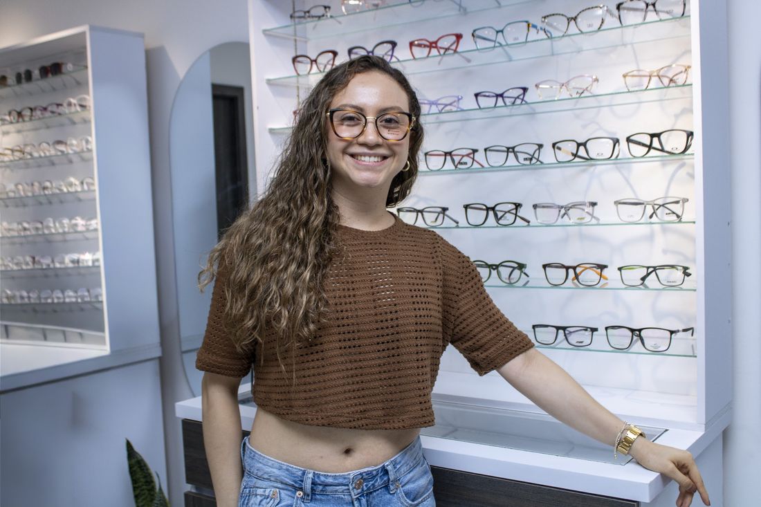 Paciente con sus gafas nuevas frente a la pared de monturas de Enfoque 360